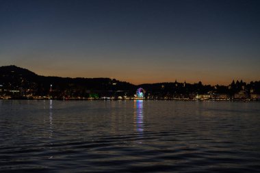 Şehir arka plan ile tekneyle görüntülenen Lucerne Gölü üzerinde günbatımı