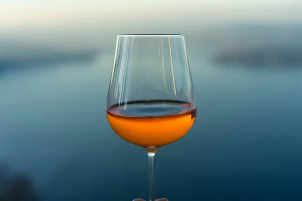 Wine glass with drink in front of blue lake iconic background Stok Foto Bebas Royalti