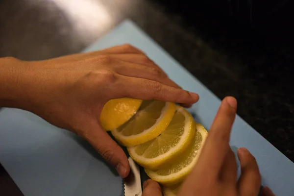 En rodajas de limón en la cocina con cuchillo y mano — Foto de Stock