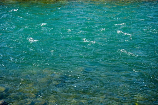 Turquoise rivierwater met kleine golven en stenen — Stockfoto