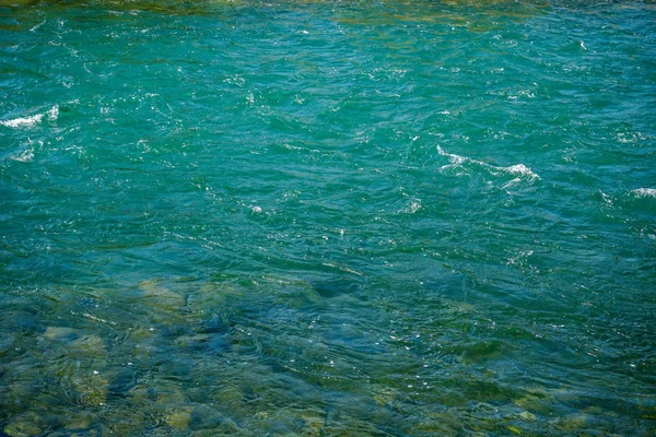 Turquoise rivierwater met kleine golven en stenen — Stockfoto