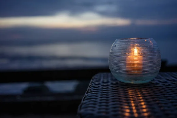 Vela em uma mesa com vista para a praia ao pôr do sol — Fotografia de Stock