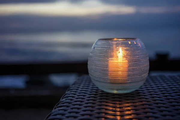 Lilin di atas meja dengan pemandangan pantai saat matahari terbenam Stok Lukisan  