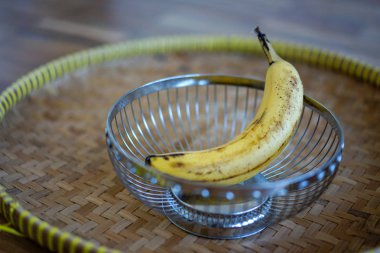 ahşap zikzak plaka üzerinde metal sepet içinde tek muz