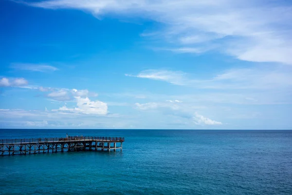 Jetée en bois et eau calme de l'océan avec ciel bleu et nuages — Photo