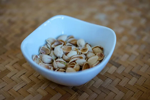 Орехи фисташки в белой керамической миске и деревянный фон — стоковое фото