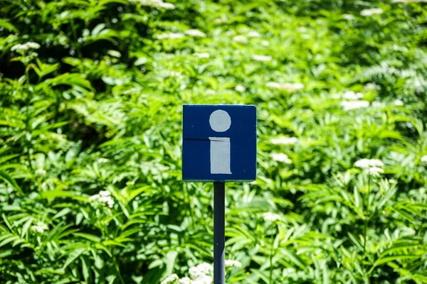 blue information sign with green garden background
