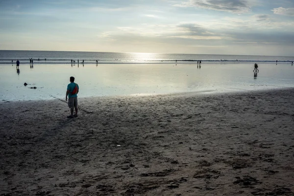 Personas en la playa en el agua al atardecer — Foto de Stock