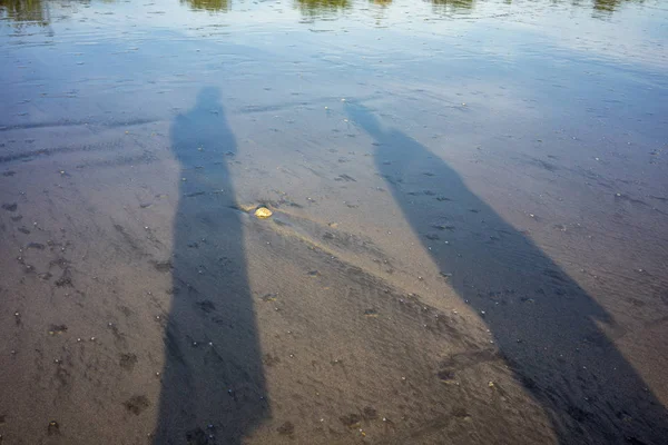 물으로 바닷가 모래에 사람 그림자 — 스톡 사진