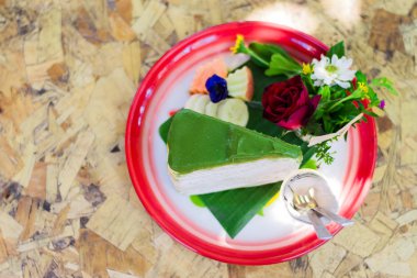 Kırmızı tepside yeşil çay kek çiçek ve meyve ahşap masada güzel yapmak var