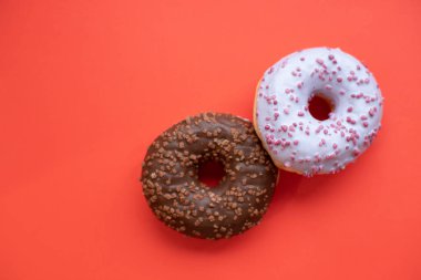 iki sırlı donut izole kırmızı background.pastel renk, pembe ve kahverengi tatlı çörek, seçici odak. Uzay kopyalayın. Minimalist kavramı