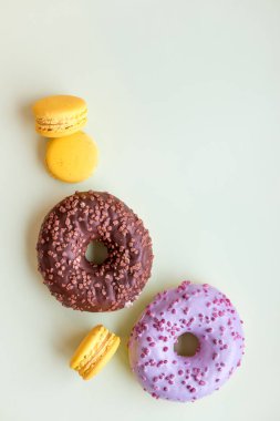 Sırlı donuts ve Bademli kurabiye. Şekerli tatlı yumuşak yeşil arka plan üzerinde izole. Buttercream ile kek. limon, sarı macaron kurabiyeler. Pop art renk stili. Seçici odak. Kopya alanı