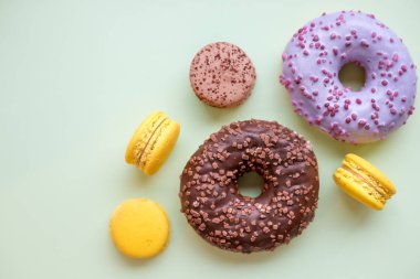 Renkli donut ve macaroons ahşap masa üzerinde. Üstten görünüm kopya alanı ile. Sağlıksız ama lezzetli tatlı