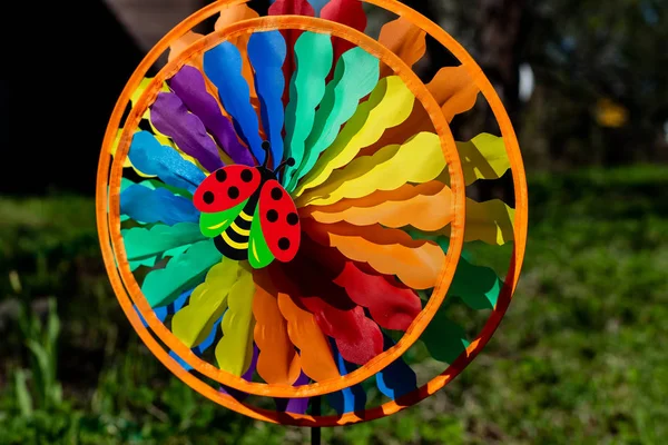 Çok renkli bir yel değirmeni oyuncak. Yeşil bahçe arka planı. çocuk oyuncaklar, Dekoratif ve renkli fırıldak spinner yel değirmenleri ortasında bir uğur böceği ve arka planda çiçeklerile çim.