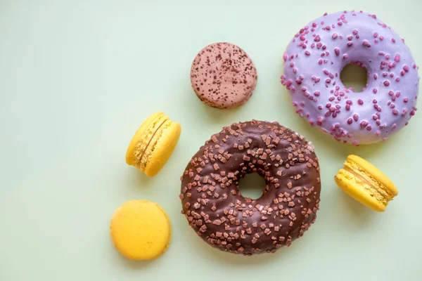 Renkli donut ve macaroons ahşap masa üzerinde. Üstten görünüm kopya alanı ile. Sağlıksız ama lezzetli tatlı