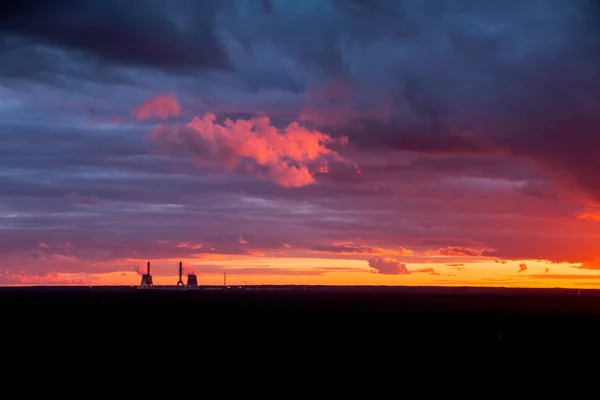 Tournage aérien de Coucher de soleil spectaculaire coloré dans la zone industrielle de la ville. Silhouettes de maisons et cheminées avec fumée. Image de drone. Espace de copie, focus sélectif sur le ciel . — Photo