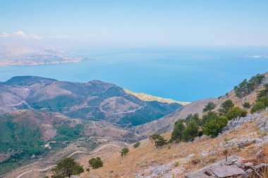 Dağ tarafı mavi gökyüzü ve okyanus kadar aşağıdaki sahilinde dolambaçlı yolda. Havadan görünümden dağlar denize. Seyahat kavramı. Kopya alanı