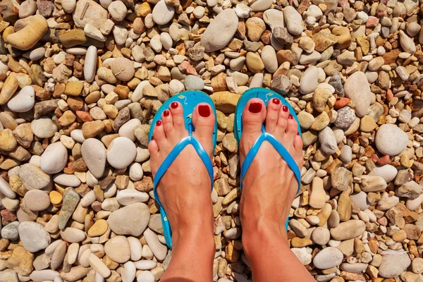 Low section of woman wearing slippers while standing on board walk.First person perspective, view on own feet. Rocky beach.Female legs wearing flip flops near sea. top view — Stock Photo, Image