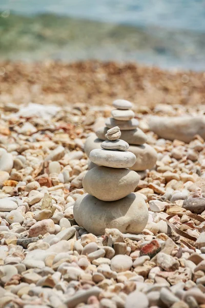 Smooth stones stacked on each other on the beach. Tower of stones for meditation on a sea. Moth sitting on top of the tower.