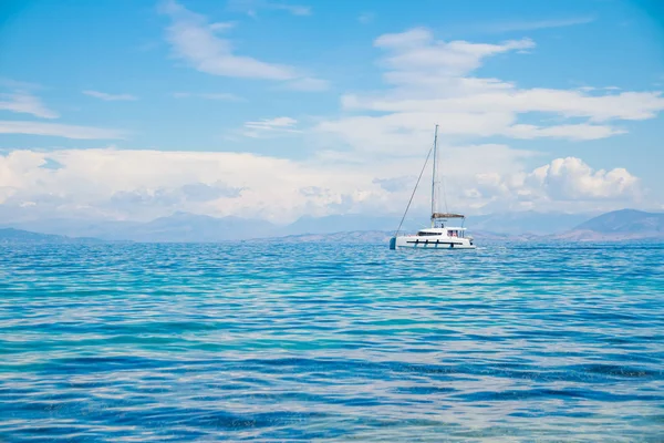 Catamarán en el mar azul.catamarán de velero blanco en el océano cerca de la playa.Barco de lujo cerca de la costa.Copiar el espacio — Foto de Stock