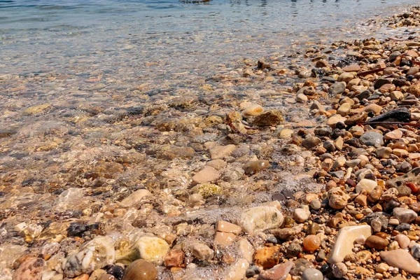 Pebble stenen door de zee. Zijdeachtige golven van blauwe zee van lange blootstelling. Selectieve aandacht. Zomervakantie op zee concept. — Stockfoto