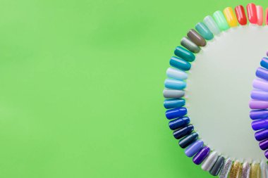 Renk örnekleri çivi. Yapay parmak çivi büyük toplama farklı renklerde boyanmış. Güzellik salon.gel vernik çivi. kadınsı tırnak sanat. Tırnak sanat tasarım tekerlek üzerinde yeşil arka plan