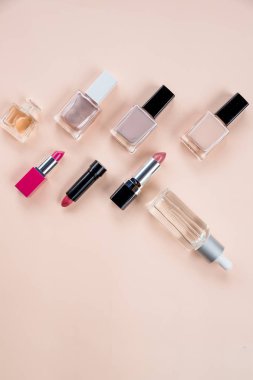 Çeşitli makyaj ürünleri pastel arka plan üzerinde renkli çerçeveli. Kozmetik, cilt bakım, parfüm, tırnak cilası, ruj düz lay ve cilt petrol şişe bej renkli bir arka plan üzerinde. Güzellik ürünleri kavramı. Kopya