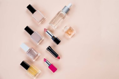 Çeşitli makyaj ürünleri pastel arka plan üzerinde renkli çerçeveli. Kozmetik, cilt bakım, parfüm, tırnak cilası, ruj düz lay ve cilt petrol şişe bej renkli bir arka plan üzerinde. Güzellik ürünleri kavramı. Kopya