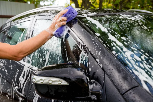 Kvinna som tvättar bilen på manuell biltvätt self service station, rengöring med skum, pressade vatten. Transport, auto, fordonet vård koncept — Stockfoto