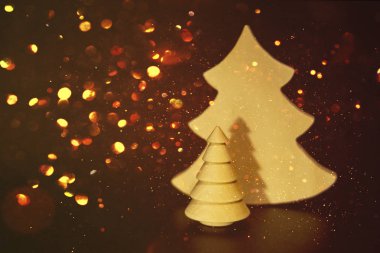 Karanlıkta altın parlak bokeh ile yaratıcı ahşap Noel ağacı oyuncaklar. Lüks zarif neşeli Noel ve mutlu yeni yıl afiş, davetiye, parlayan altın kar taneleri ile