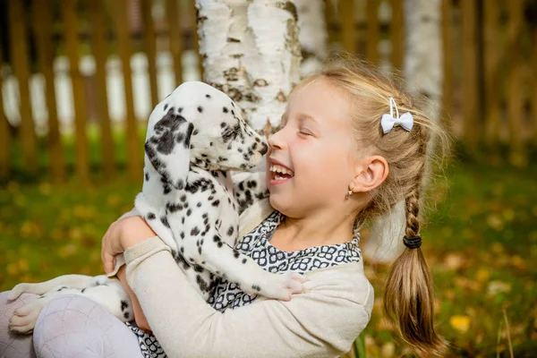 Pequeño perro con dueño feliz pasar un día en el parque jugando y divirtiéndose. Foto divertida de niña riendo, ella abrazando y jugando con hermoso cachorro dálmata. Emociones positivas de los niños juegos divertidos — Foto de Stock
