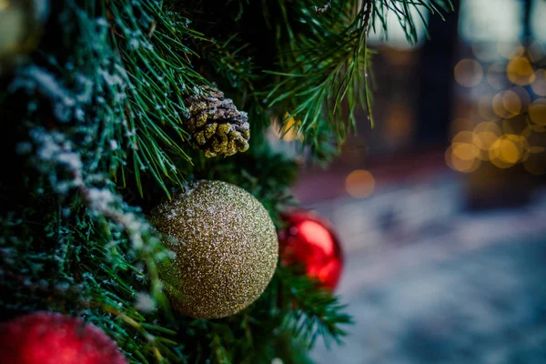 Christmas family atmosphere.Red, golden Christmas Ornament hanging on a frost covered pine tree outdoors with copy space.Christmas decoration with lots of lights.blurred lights and outdoor decorations — стоковое фото