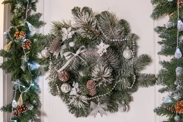 Ghirlanda decorativa natalizia di rametti di agrifoglio, edera, vischio, cedro e foglia di leyland con pigne su sfondo bianco.Ghirlanda fatta a mano di Natale su sfondo di legno. Decorazione d'interni festiva — Foto Stock