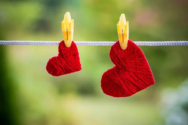 Dois corações vermelhos pendurados na corda fixada por varandas isoladas em fundo verde borrado. Dia dos Namorados e conceito de família feliz. Espaço de cópia . — Fotografia de Stock