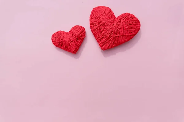 Een handgemaakte haakwerk wol organische rood hart. twee rode garen bal als een hart op de roze achtergrond. Rood hart gemaakt van wol garen en haak hart. De dag van Valentijnskaarten. Kopieer ruimte. liefde en gevoelens. — Stockfoto
