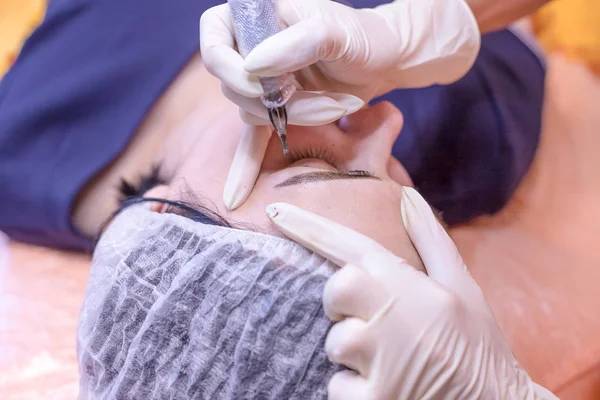 Permanent makeup. Permanent tattooing of eyebrows. Cosmetologist applying permanent make up on eyebrows- eyebrow tattoo.facial treatment in the beauty salon