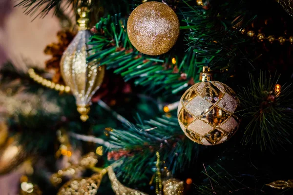 Ramo di abete con palle e luci festive sullo sfondo di Natale con scintilli.Palla d'oro con glitter come ornamento decorativo di Natale su un albero artificiale.Decorazione di Capodanno. — Foto Stock