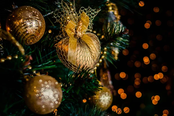 Ramo di abete con palle e luci festive sullo sfondo di Natale con scintilli.Palla d'oro con glitter come ornamento decorativo di Natale su un albero artificiale.Decorazione di Capodanno. — Foto Stock