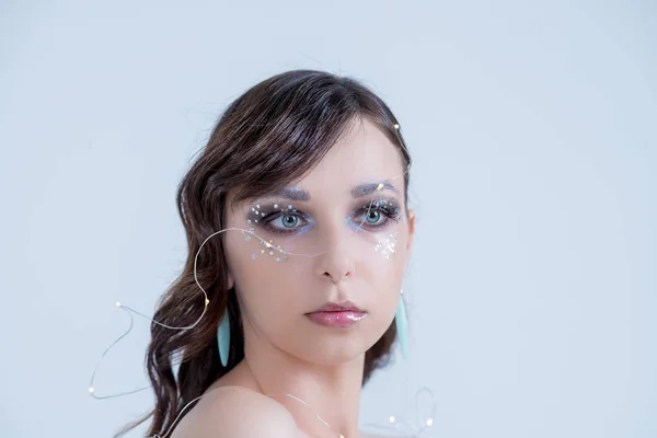 Beautiful High Fashion Make Up Hair style glitter fancy with crystal sparkling wink, pearl, beads, garland, gel lips, Crystals,copy space.Winter Beauty Woman. Holiday Make-up.