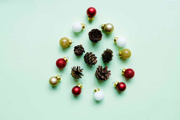 Vánoční strom a šišky na pozadí pastelové zelené, minimalismus složení. Byt ležel, kreativní design. Vánoční strom vyrobený z dekorací. svátků a oslav kreativní koncept. Nový rok a — Stock fotografie