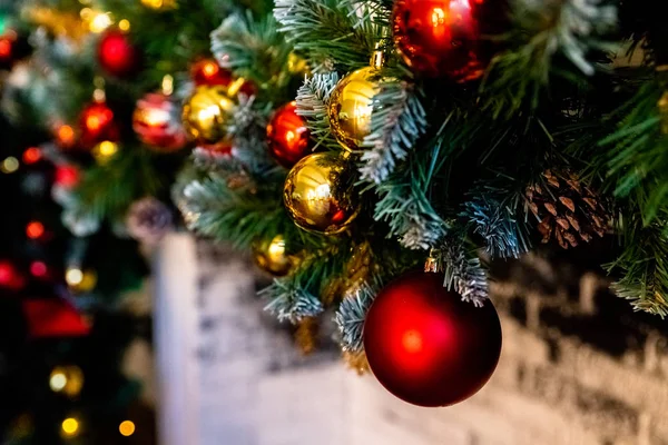 Рождественский камин, Xmas Lights Decoration, Tree Branches.Decorated елка, на переднем плане шары на ветках и луки. Классические апартаменты с камином. Рождественский вечер . — стоковое фото