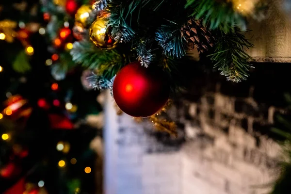 Camino di Natale, Luci di Natale Decorazione, rami d'albero. Albero di Natale decorato, in primo piano palle sui rami e archi. Appartamenti classici con camino. Serata di Natale . — Foto Stock