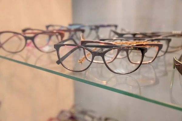 Fila de gafas de lujo en una tienda de ópticas.Gafas graduadas en óptica.Vista lateral de gafas ópticas de moda, colgando en conjunto transparente con otras gafas. Visión mejorando y protegiendo. médico —  Fotos de Stock