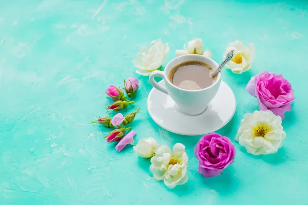 Coloridas flores y taza de café de la mañana sobre fondo azul. el concepto de bebida caliente, café para el desayuno. mesa romántica con copa de bebida caliente y rosas.beautiful flores para —  Fotos de Stock