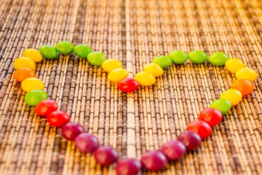 Şeker bir kalp gibi saman peçete üzerinde bir kalp shape.colorful bonbon şekillendirme. Bambu peçete mat doku. Ahşap çizgili. 14 Şubat için Günaydın tebrik kartı