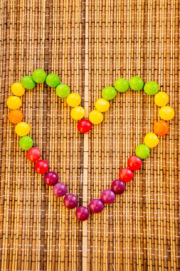 Şeker bir kalp gibi saman peçete üzerinde bir kalp shape.colorful bonbon şekillendirme. Bambu peçete mat doku. Ahşap çizgili. 14 Şubat için Günaydın tebrik kartı