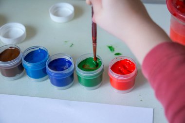 Guaj ve su resim ve çocuk artwork.the çocuk yapıyor beyaz paper.child üzerinde çizim için paint.kindergarten, eğitim kavramı onun fırça daldırma. Paintbrush resim çizim çocuğun el