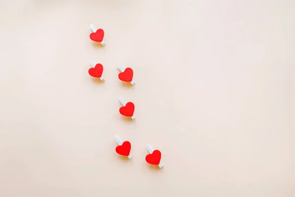 Rode harten op wasknijpers voor het aanbrengen van een sticker die zegt dat ik hou van jou op beige achtergrond. Happy Valentines Day en 8 maart, internationale dag van de Womens Concept. Plaats voor tekst, romantische groeten — Stockfoto