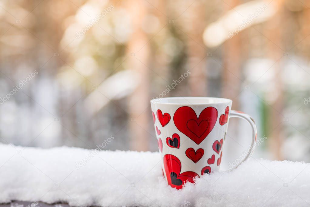 Valentines Day with red cup coffee on snow white background, copy space Valentine Concept.Warm and romantic atmosphere in a cold winter Valentines Day. Hot drinks outdoor.