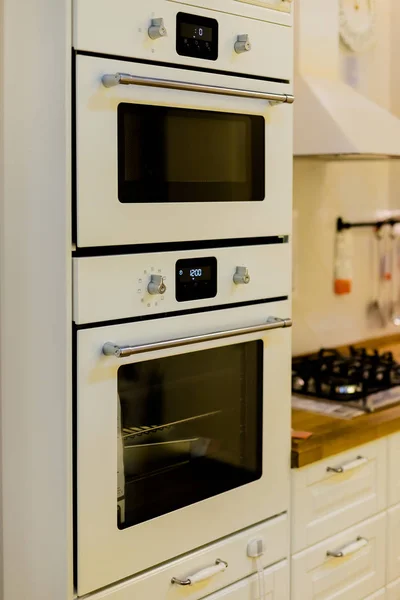 Κομψή κουζίνα εσωτερικό με λευκό, γκρι έπιπλα. Μοντέρνο εσωτερικό του κουζίνα με ηλεκτρική κουζίνα και φούρνο. Μοτίβο κεραμιδιών δαπέδων και τοίχων στην κουζίνα. Κατακόρυφη προβολή της σύγχρονης κουζίνας — Φωτογραφία Αρχείου